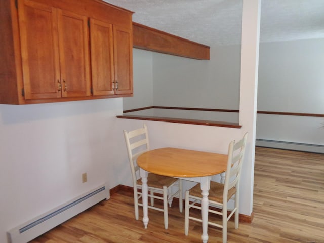 dining area with a baseboard heating unit and light hardwood / wood-style flooring