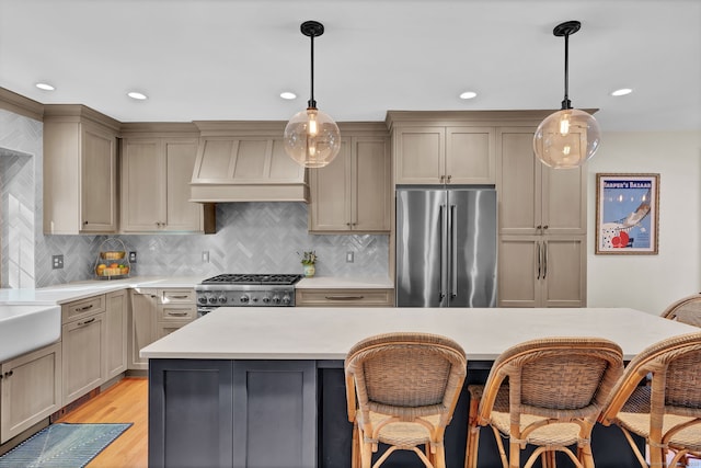 kitchen with premium range hood, appliances with stainless steel finishes, decorative light fixtures, and light hardwood / wood-style floors