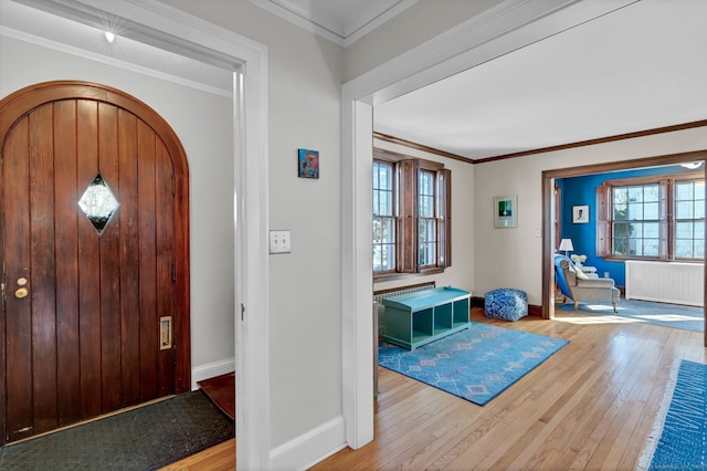 entryway with crown molding, plenty of natural light, radiator heating unit, and light hardwood / wood-style flooring