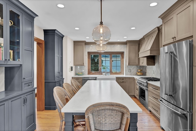 kitchen featuring pendant lighting, sink, gray cabinets, premium appliances, and custom exhaust hood