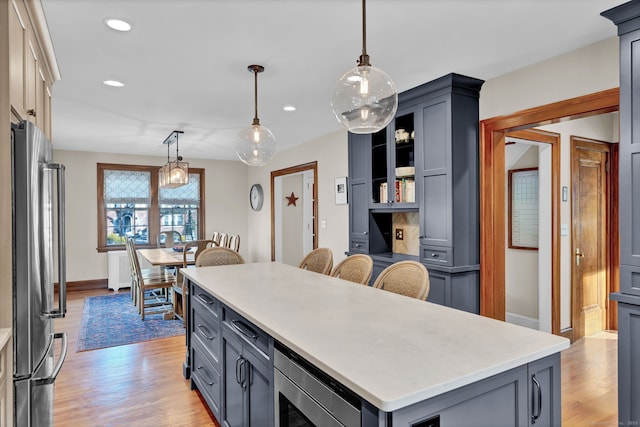 kitchen with pendant lighting, gray cabinetry, stainless steel appliances, a center island, and light wood-type flooring