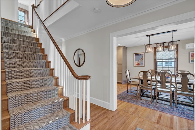 stairs with crown molding, wood-type flooring, a wall unit AC, and a wealth of natural light