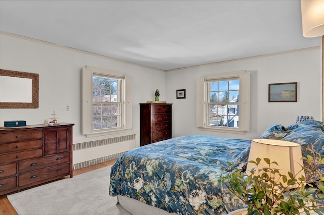 bedroom featuring hardwood / wood-style flooring, radiator, and multiple windows