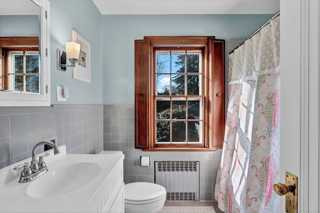 bathroom with vanity, radiator heating unit, tile walls, and toilet