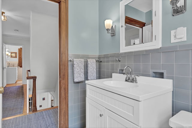 bathroom featuring vanity, toilet, and tile walls