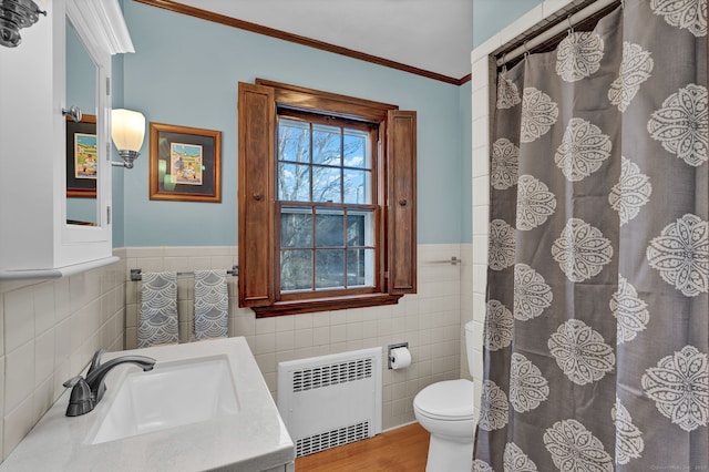 bathroom featuring radiator, tile walls, vanity, ornamental molding, and toilet