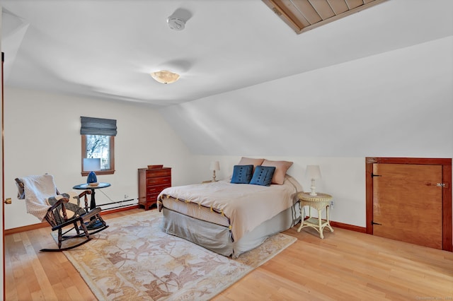 bedroom with vaulted ceiling, light hardwood / wood-style floors, and a baseboard radiator