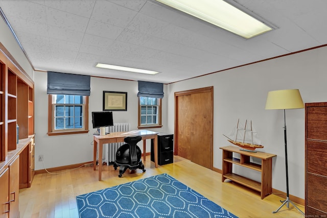 home office with crown molding and light hardwood / wood-style floors