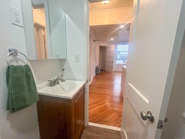 bathroom with hardwood / wood-style flooring, vanity, and radiator heating unit