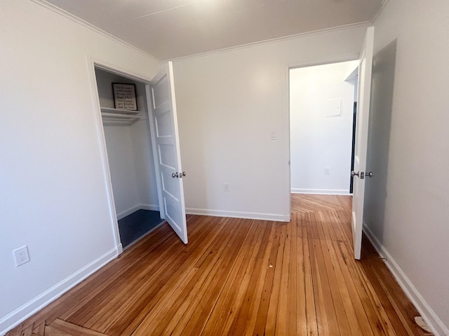 unfurnished bedroom featuring wood-type flooring, ornamental molding, and a closet