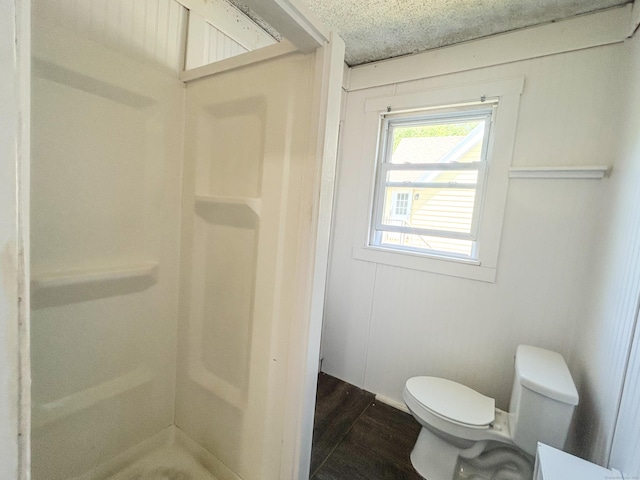 bathroom with hardwood / wood-style flooring, walk in shower, a textured ceiling, and toilet