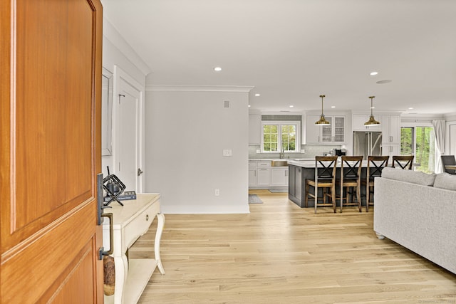 foyer entrance featuring crown molding, sink, and light hardwood / wood-style flooring