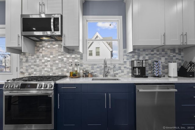 kitchen featuring stainless steel appliances, white cabinetry, sink, and backsplash