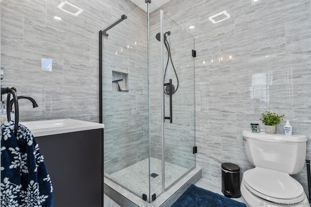 bathroom with walk in shower, vanity, toilet, and tile walls