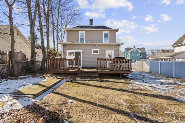 snow covered rear of property with a deck