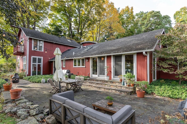 rear view of house featuring entry steps, outdoor dining area, an outdoor hangout area, roof with shingles, and a patio area