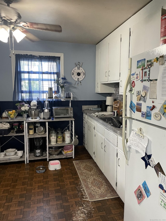 kitchen featuring ceiling fan, dark parquet floors, white fridge, and white cabinets