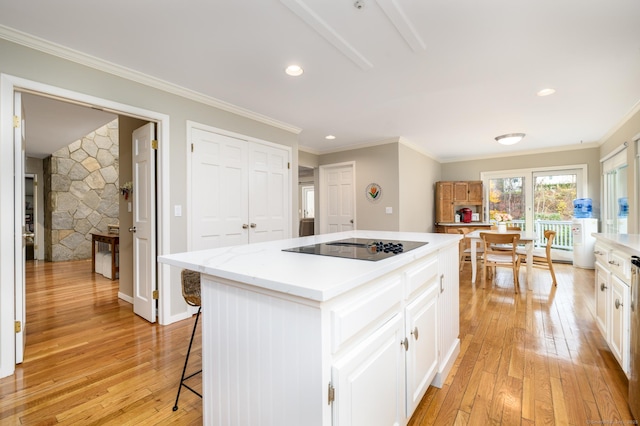 kitchen with a kitchen island, white cabinets, light hardwood / wood-style floors, crown molding, and black electric cooktop