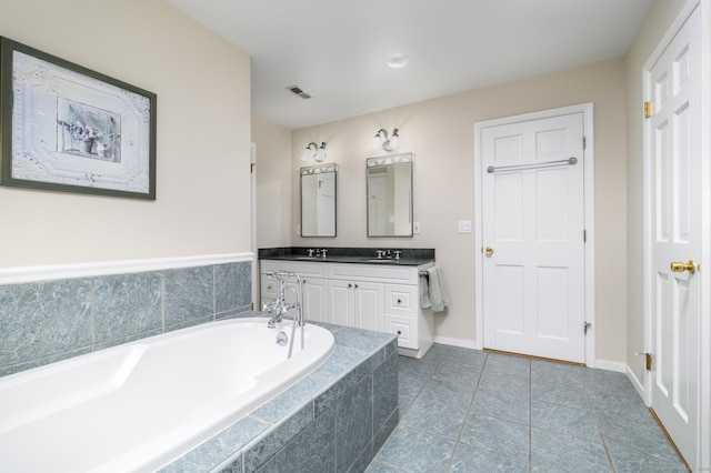 bathroom with tile patterned floors, vanity, and tiled tub