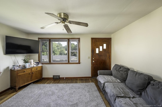 living room with baseboards, visible vents, dark wood finished floors, and a ceiling fan