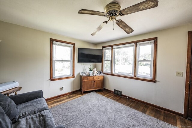 living area with dark hardwood / wood-style flooring, ceiling fan, and a healthy amount of sunlight