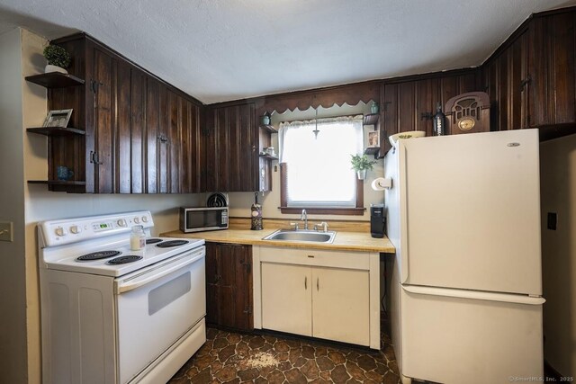 kitchen featuring sink, white appliances, dark brown cabinetry, cream cabinets, and a textured ceiling