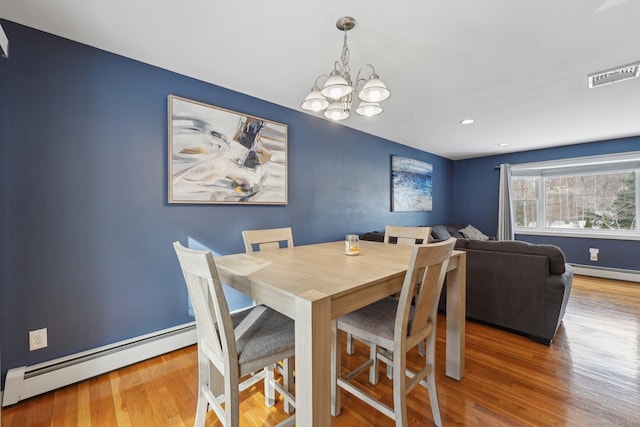 dining room featuring baseboard heating, a chandelier, and wood-type flooring