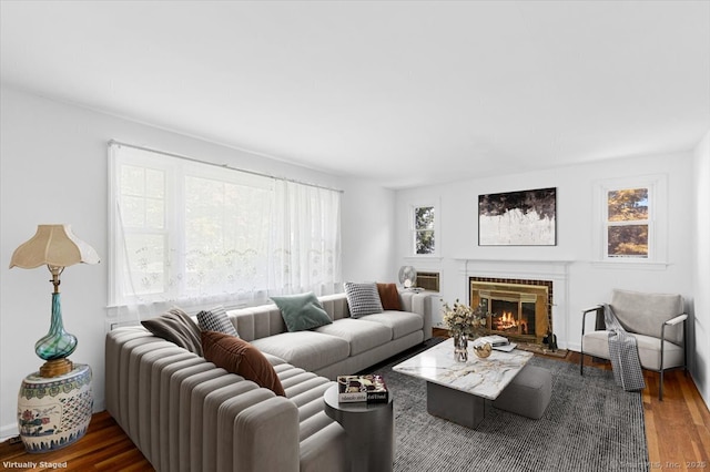 living room with dark wood-type flooring, plenty of natural light, and a brick fireplace