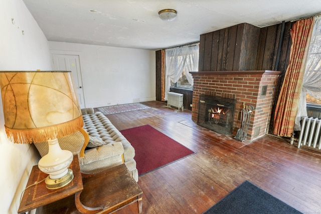 living room featuring a fireplace, hardwood / wood-style flooring, and radiator heating unit