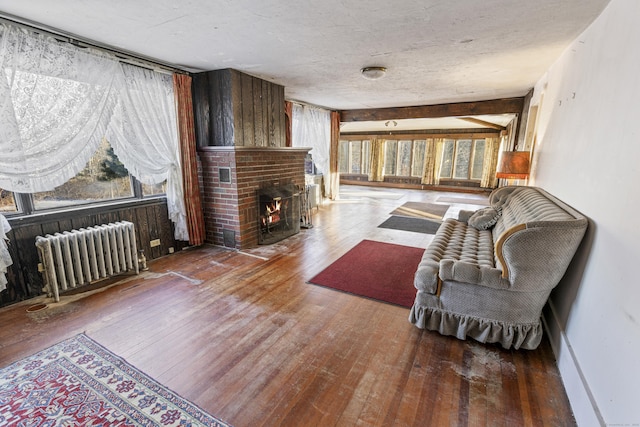 living room with hardwood / wood-style flooring, radiator, a brick fireplace, and a textured ceiling