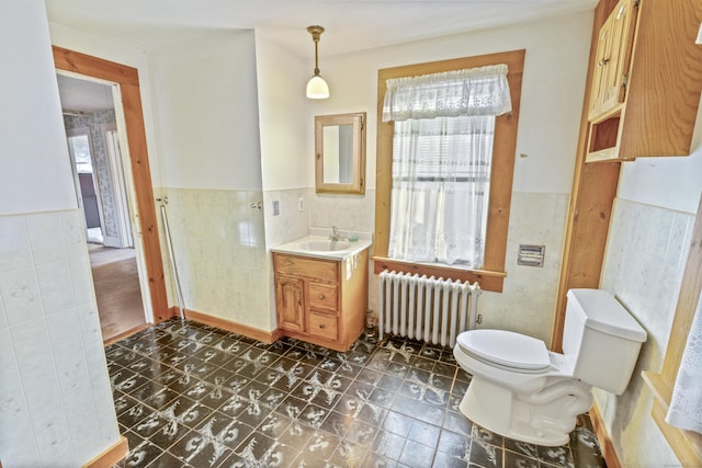 bathroom with tile walls, radiator, vanity, and toilet