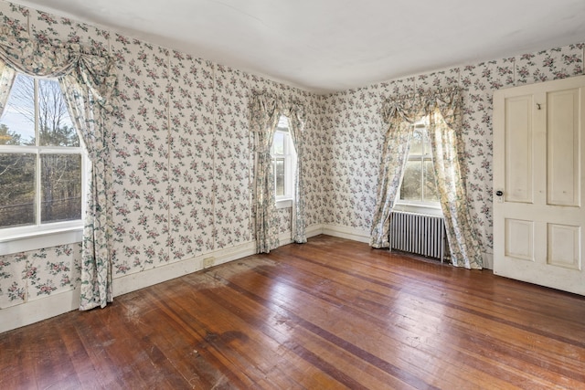 spare room featuring radiator heating unit and hardwood / wood-style floors