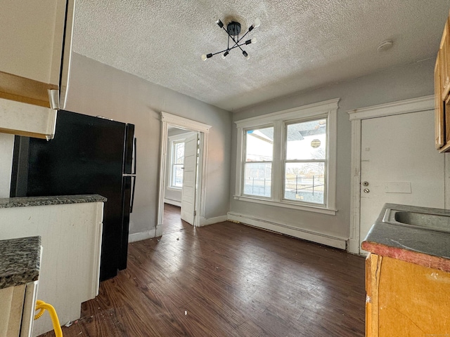 kitchen featuring black fridge, a baseboard radiator, dark hardwood / wood-style flooring, and a textured ceiling