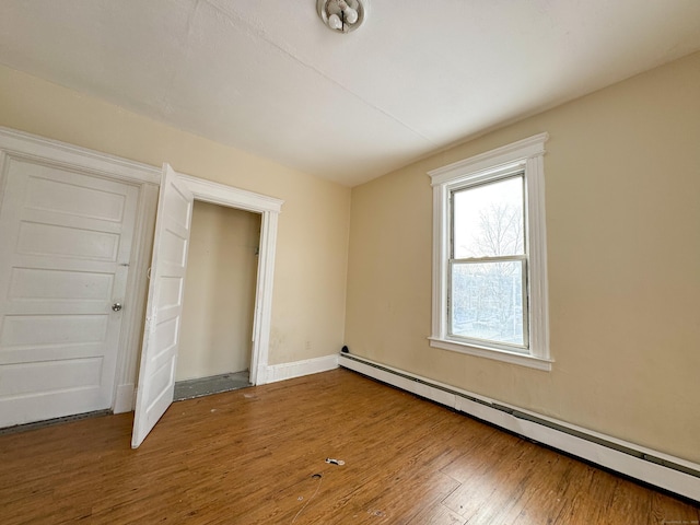 unfurnished bedroom with baseboard heating and hardwood / wood-style floors