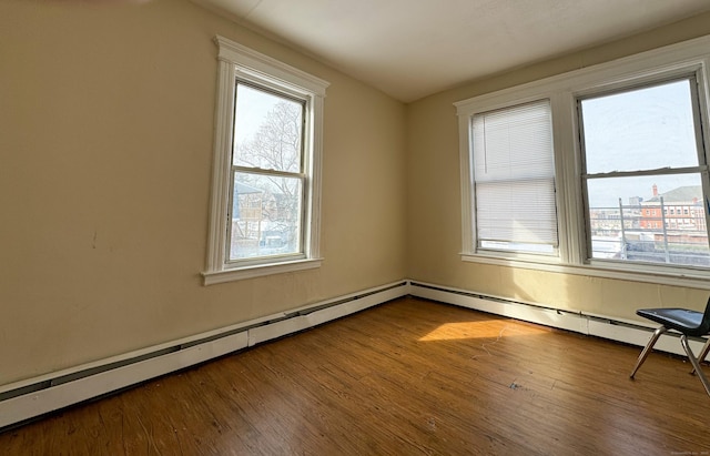 empty room featuring hardwood / wood-style floors and a baseboard heating unit