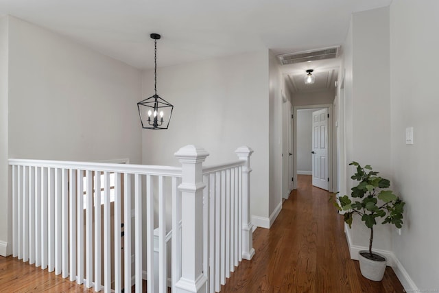 hallway with hardwood / wood-style floors and a notable chandelier