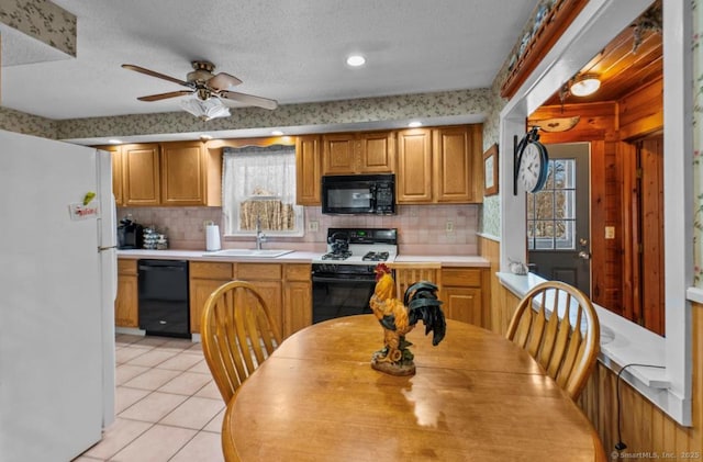 kitchen with sink, light tile patterned floors, tasteful backsplash, black appliances, and a textured ceiling