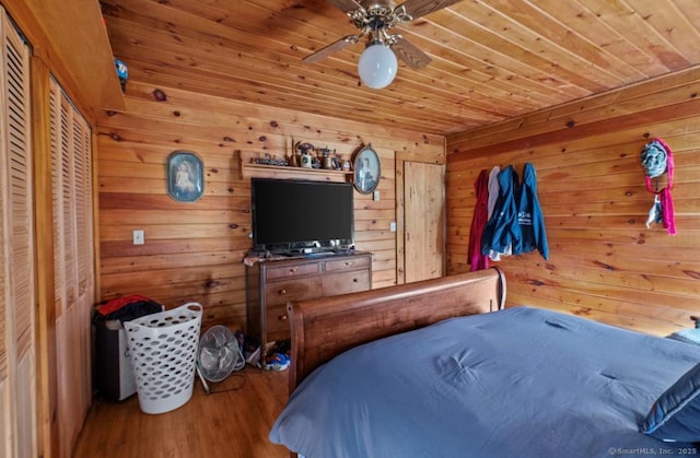 bedroom with hardwood / wood-style floors, wooden ceiling, ceiling fan, and wood walls