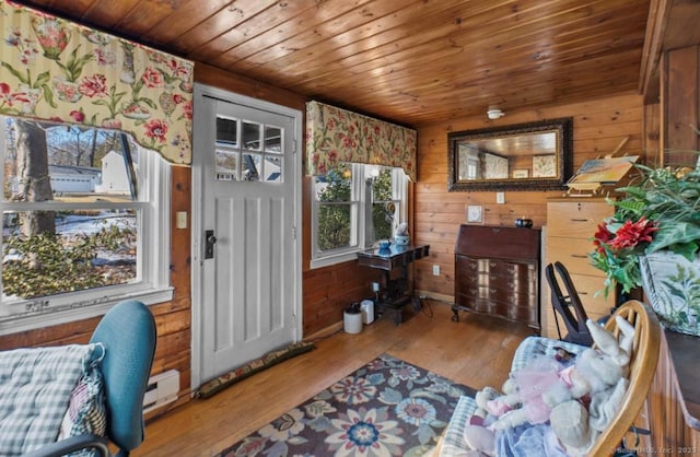 interior space with hardwood / wood-style floors, wooden ceiling, wood walls, and a baseboard heating unit