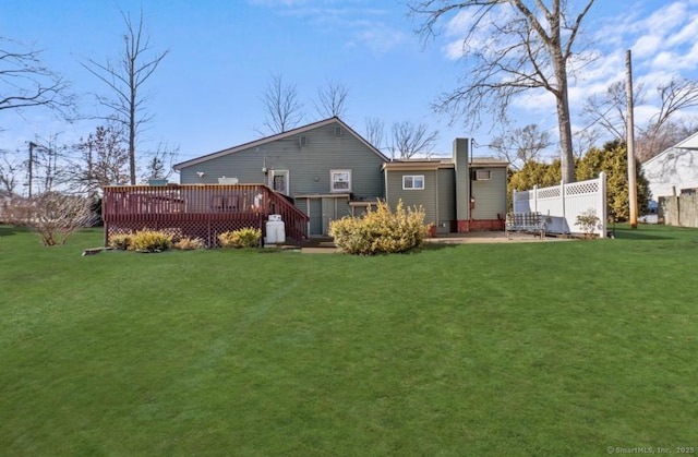 rear view of house featuring a wooden deck and a yard