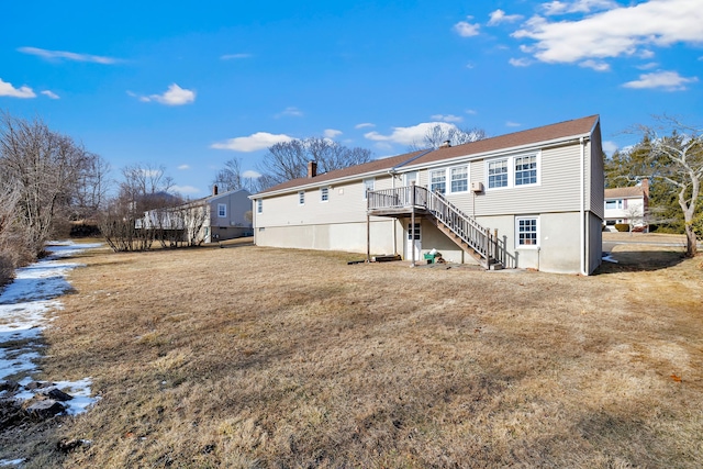 back of property featuring a wooden deck and a lawn