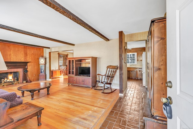 living room with beamed ceiling and a brick fireplace