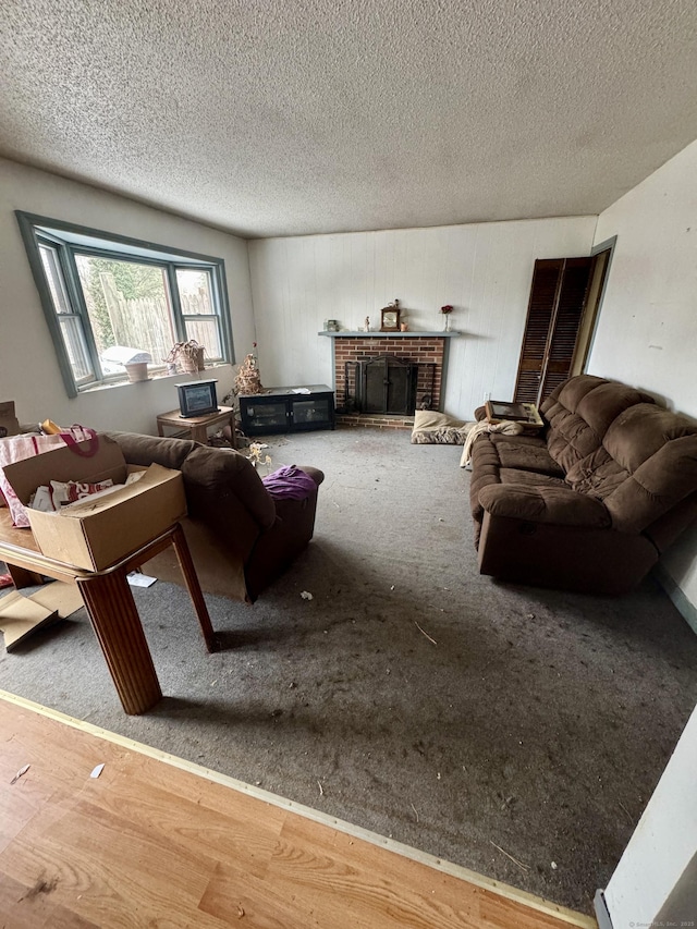 carpeted living room featuring a brick fireplace and a textured ceiling