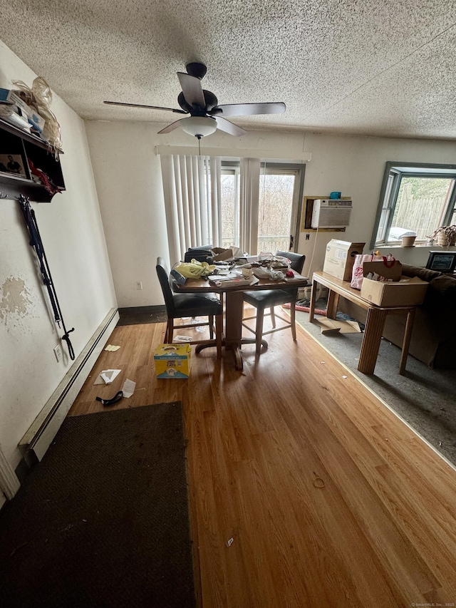 dining space with ceiling fan, wood-type flooring, a textured ceiling, a baseboard radiator, and an AC wall unit