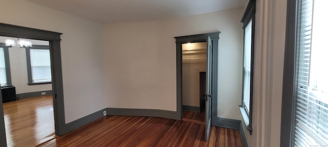 unfurnished room with radiator heating unit, dark hardwood / wood-style flooring, a chandelier, and a wealth of natural light