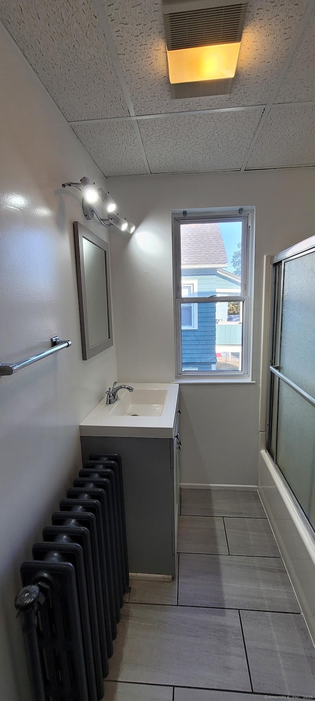 bathroom featuring vanity, a drop ceiling, and shower / bath combination with glass door