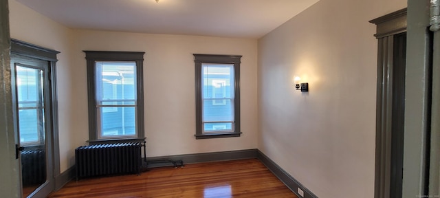 empty room featuring hardwood / wood-style flooring and radiator heating unit