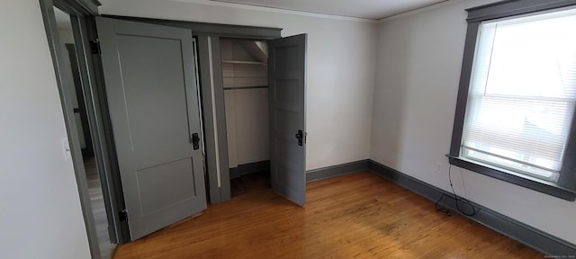 unfurnished bedroom with ornamental molding, light hardwood / wood-style floors, and a closet