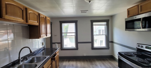 kitchen with tasteful backsplash, sink, stainless steel appliances, and hardwood / wood-style floors