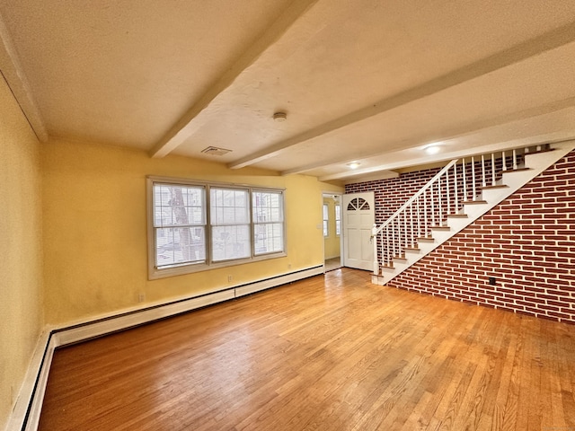 unfurnished living room featuring beamed ceiling, a baseboard radiator, brick wall, and light wood-type flooring